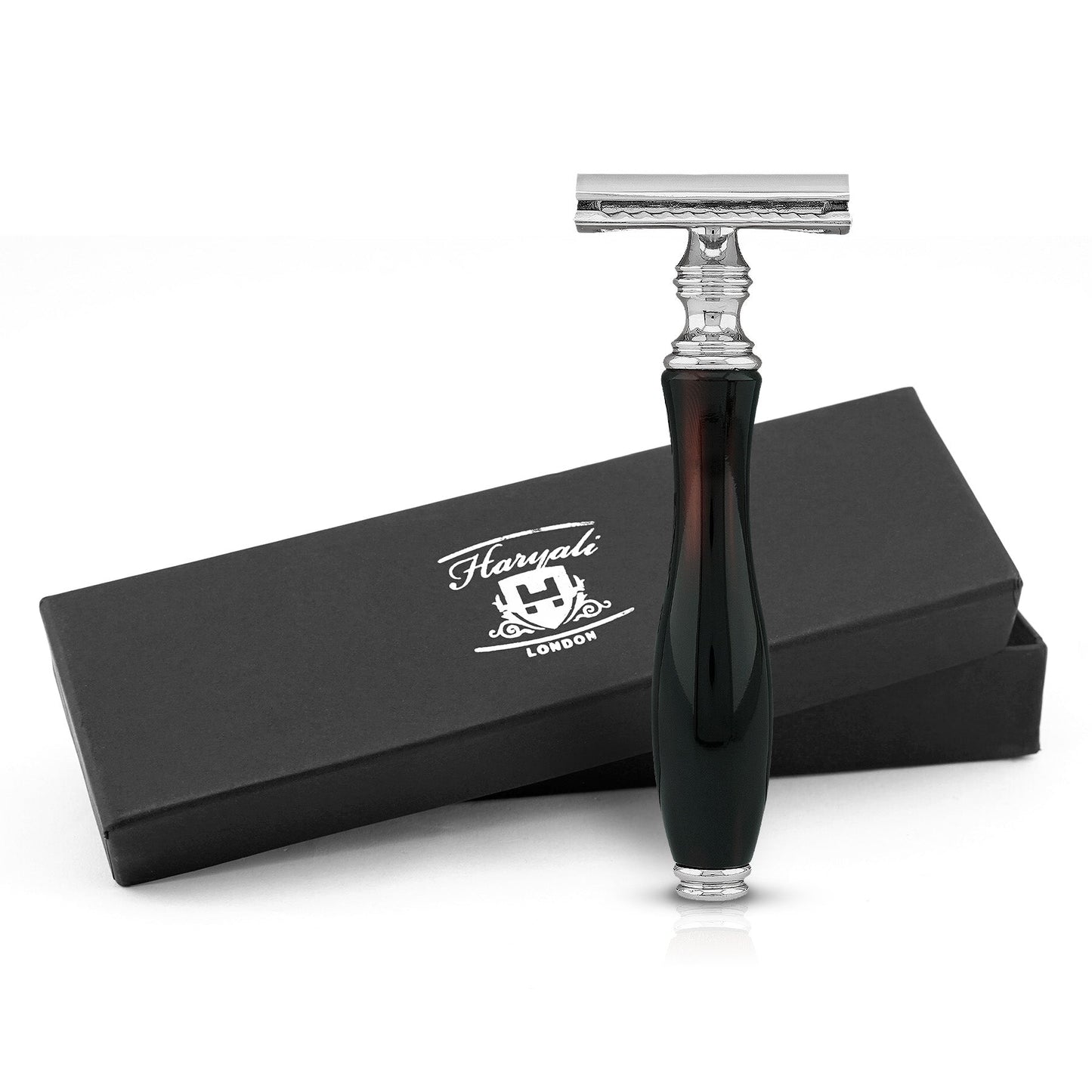 A black and red safety razor with a glass-like grip, displayed alongside its black box packaging with the Haryali London logo.