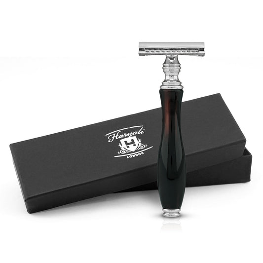A black and red safety razor with a glass-like grip, displayed alongside its black box packaging with the Haryali London logo.