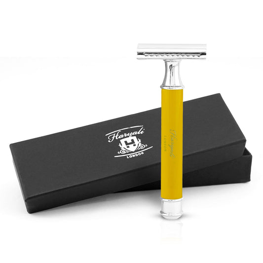 A yellow safety razor with a metal handle, branded 'Haryali London', displayed alongside its black box packaging with the brand name and logo.