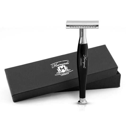 A black double edge safety razor with a branded handle, displayed alongside its black box packaging with the Haryali London logo.